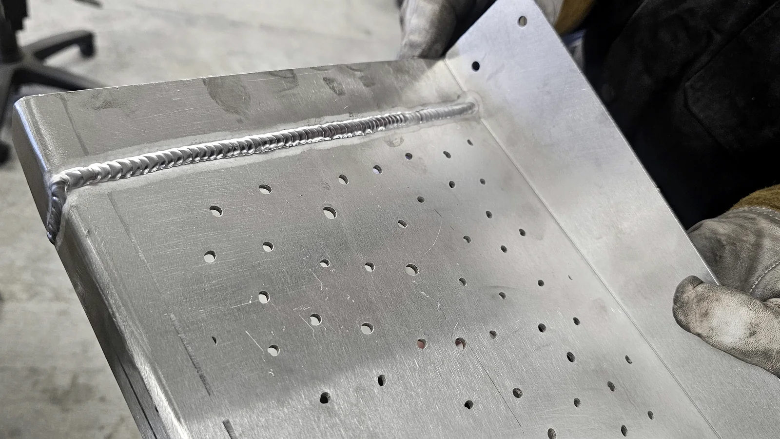 Fabricator holding a finished aluminium weld for inspection