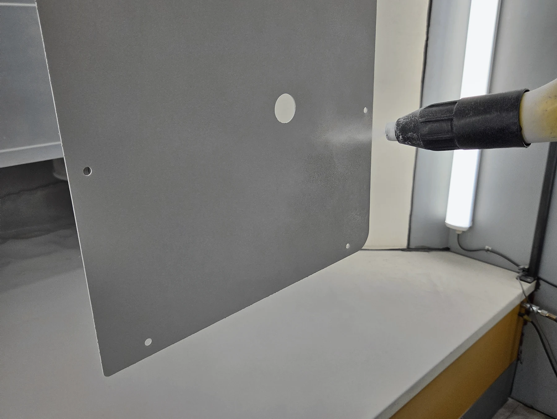 Powder coating being applied evenly to a fabricated metal panel